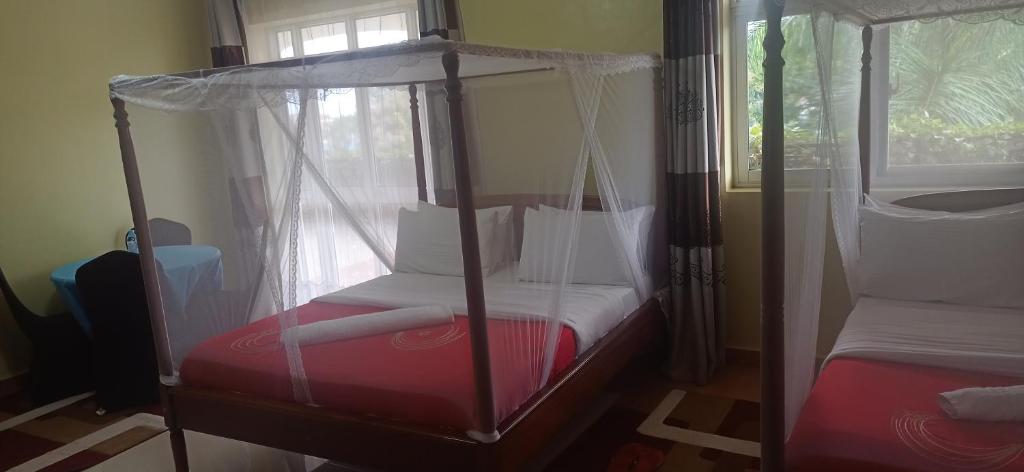 a bedroom with a four poster bed with a window at ROSEVILLA HOTEL Limited in Arua