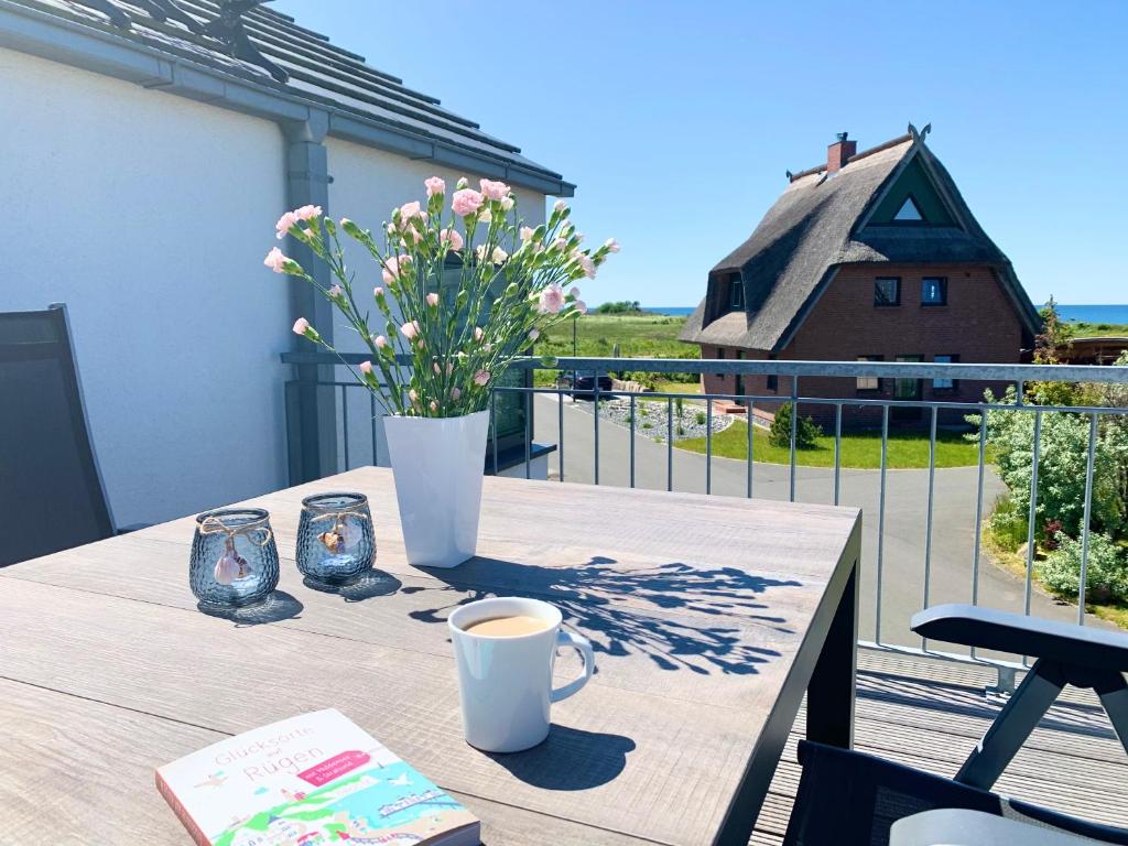 een tafel met een vaas met bloemen en een kopje koffie bij Ferienwohnung Wasser mit Sauna Kamin Meerblick und Dachterrasse nahe Ostsee auf Rügen in Dranske