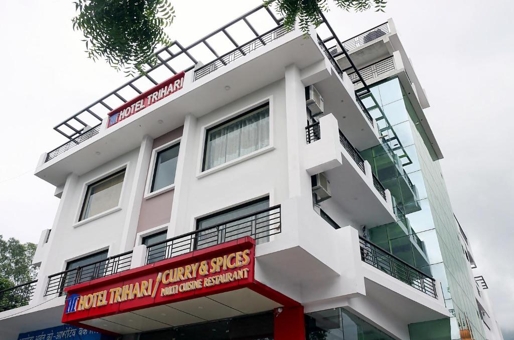 a white building with red signs on it at Hotel Trihari in Rishīkesh