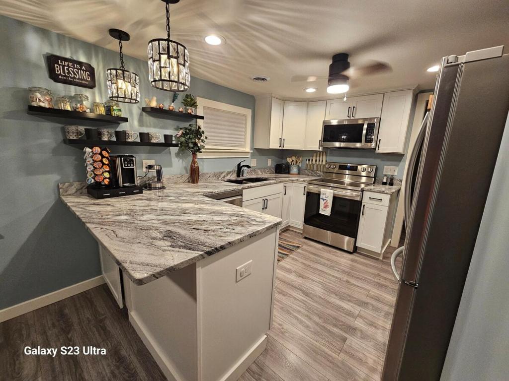 a kitchen with white cabinets and a granite counter top at Reel Relaxin Retreat to Getaway! in Houghton Lake