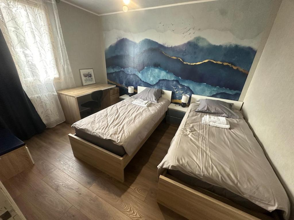 a bedroom with two beds and a painting on the wall at Maison individuelle, 3chambres, avec parking in Le Grand-Quevilly