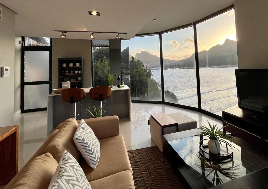 a living room with a couch and a large group of windows at The Leopard Rock Suite with uninterrupted beach views in Hout Bay