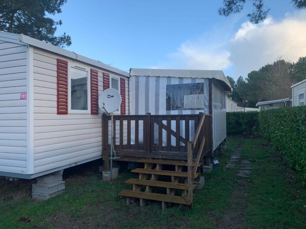 una piccola casa bianca con un portico e una scala di Mobil home 3 chambres 2 sdb 282 a Pont-Aven