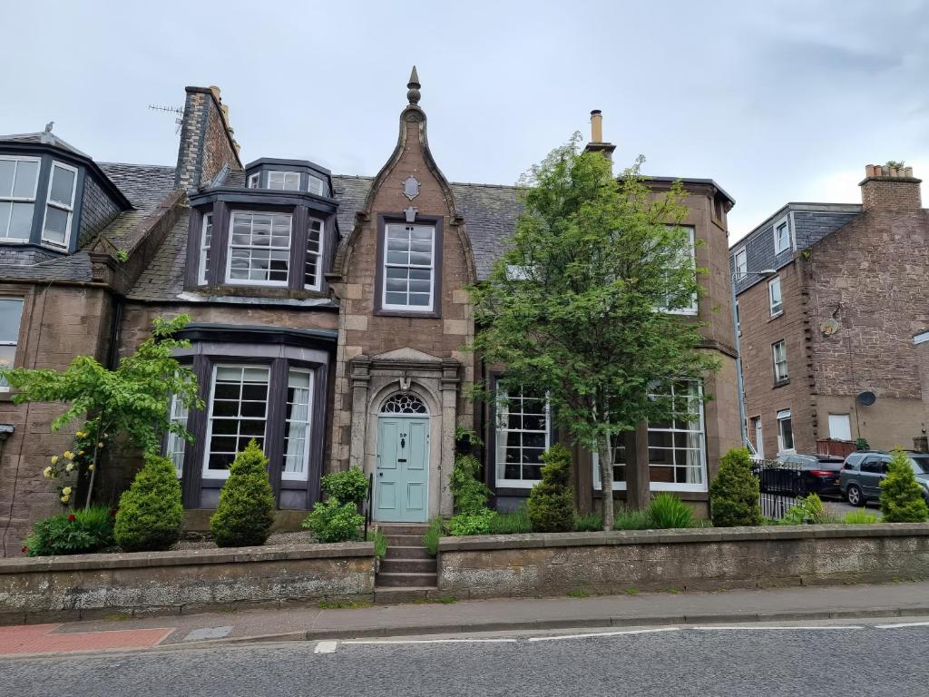 una vieja casa de ladrillo con una puerta azul en Rowan Tree House, en Brechin