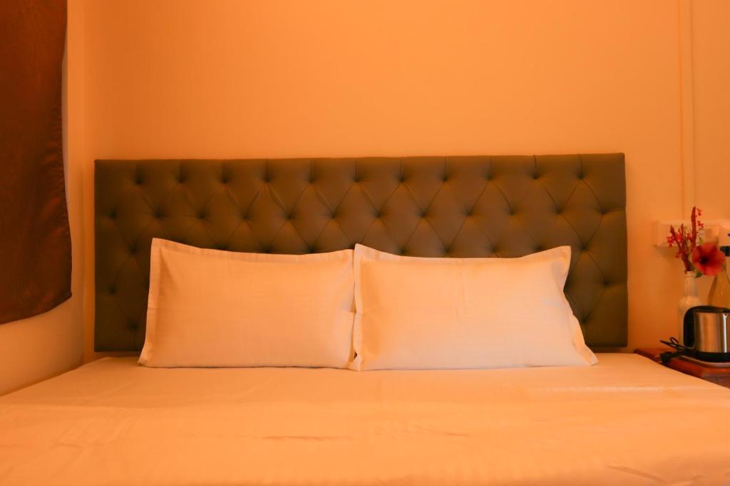 a bed with a green headboard and two white pillows at Raindrop Homestay Havelock in Sir William Peel Island