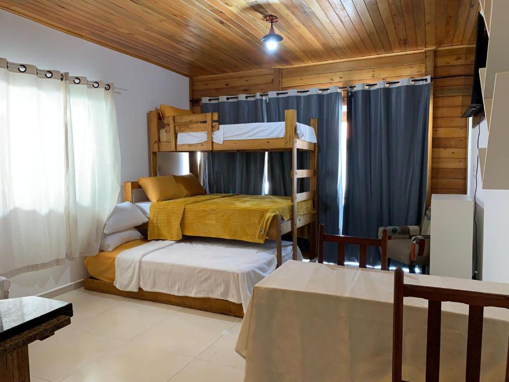 Un dormitorio con dos literas y una mesa. en Canto Gira Sol - Estúdio Girassol, en Penha