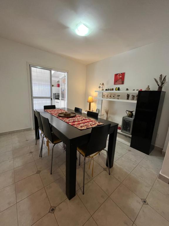 a dining room with a black table and chairs at Casa Matteo con quincho, patio y cochera in Las Grutas