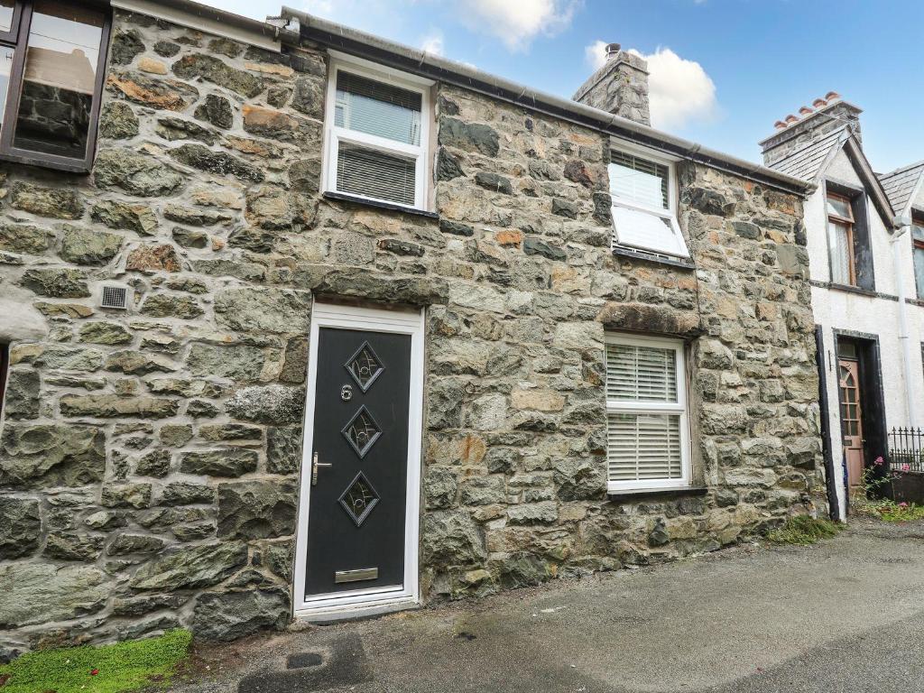 una vieja casa de piedra con una puerta negra en 6 Upperfield Street, en Dolgellau