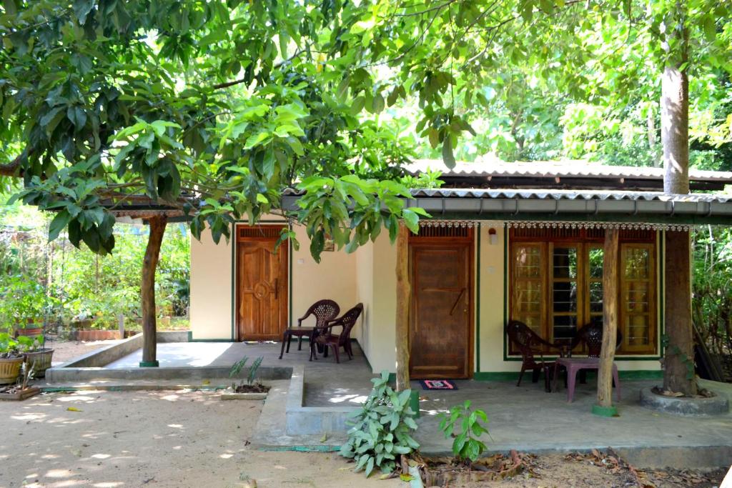 a house with wooden doors and chairs under a tree at Sigiriya Freedom Lodge in Dambulla