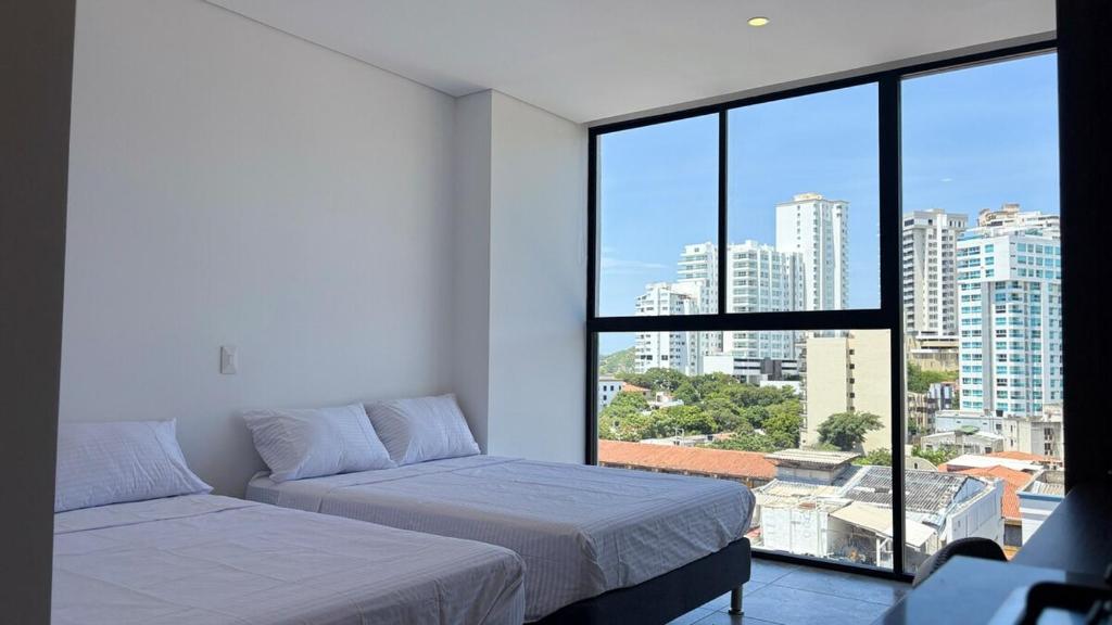 a bedroom with two beds and a large window at Exclusivo Aparta Suite en el Rodadero Ideal para 4 pax in Santa Marta
