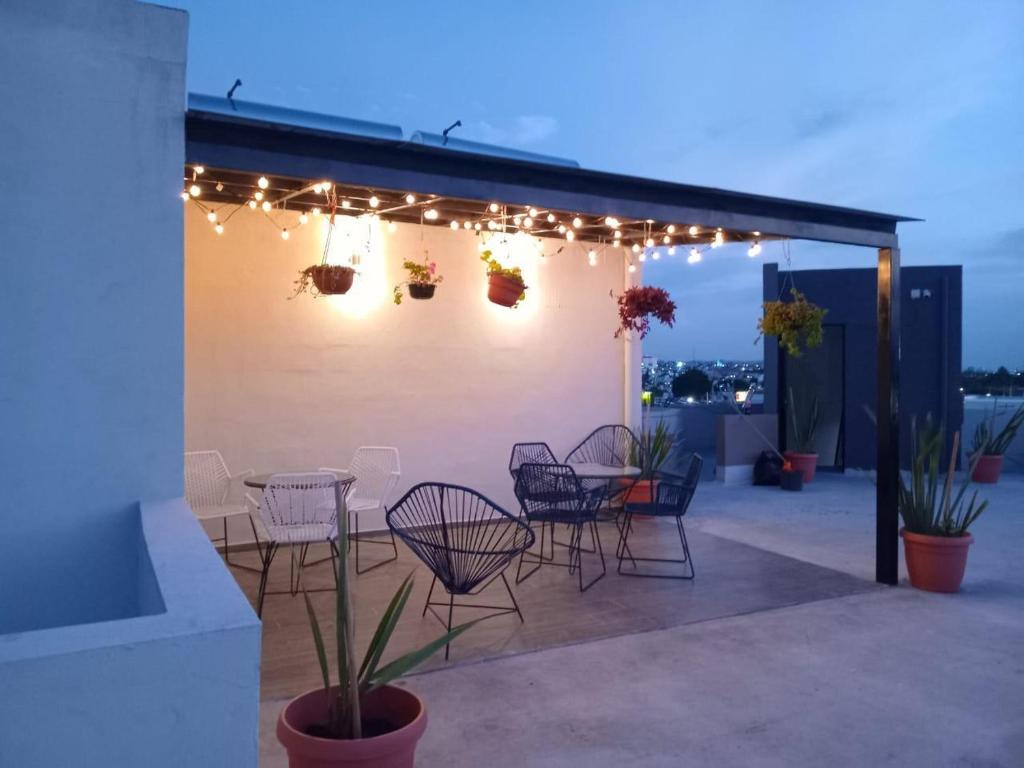 un patio con sillas, una mesa y luces en Living Alameda, en Querétaro