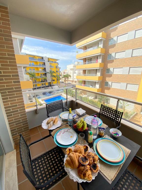 a table with plates of food on a balcony at Exclusive Apartment in Quarteira Walk to Beach in Quarteira