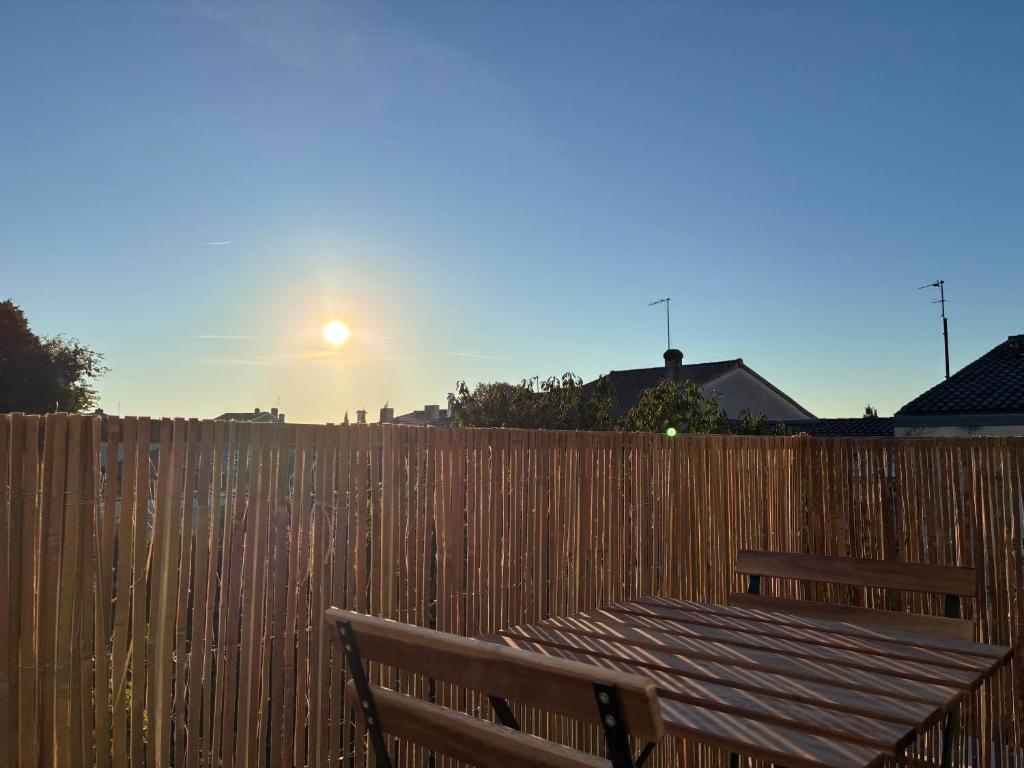 a wooden fence with a wooden table and a bench at chambre avec salle de bain, cuisine, balcon, clim et parking privé ,bordeaux centre Nansouty in Bordeaux