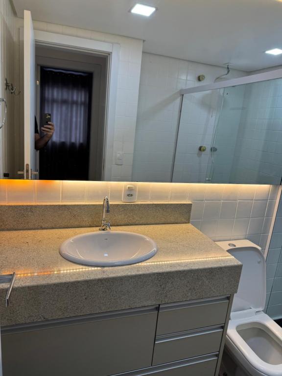 a bathroom with a sink and a mirror and a toilet at Super Central - Fácil acesso a tudo - TownHouse in Blumenau