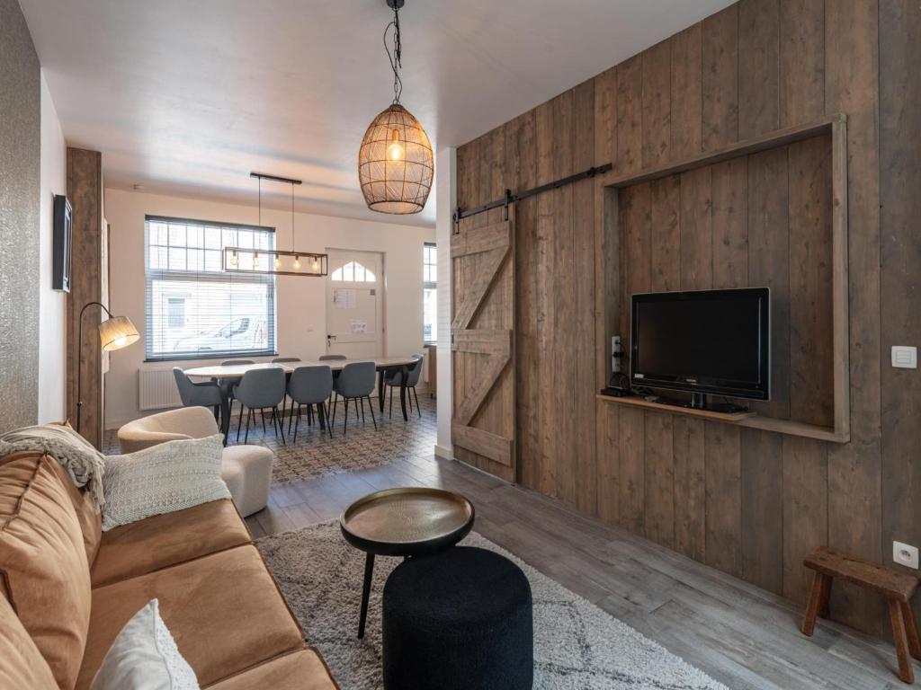 a living room with a couch and a tv on a wall at Huis Hendrik Geeraert in Nieuwpoort