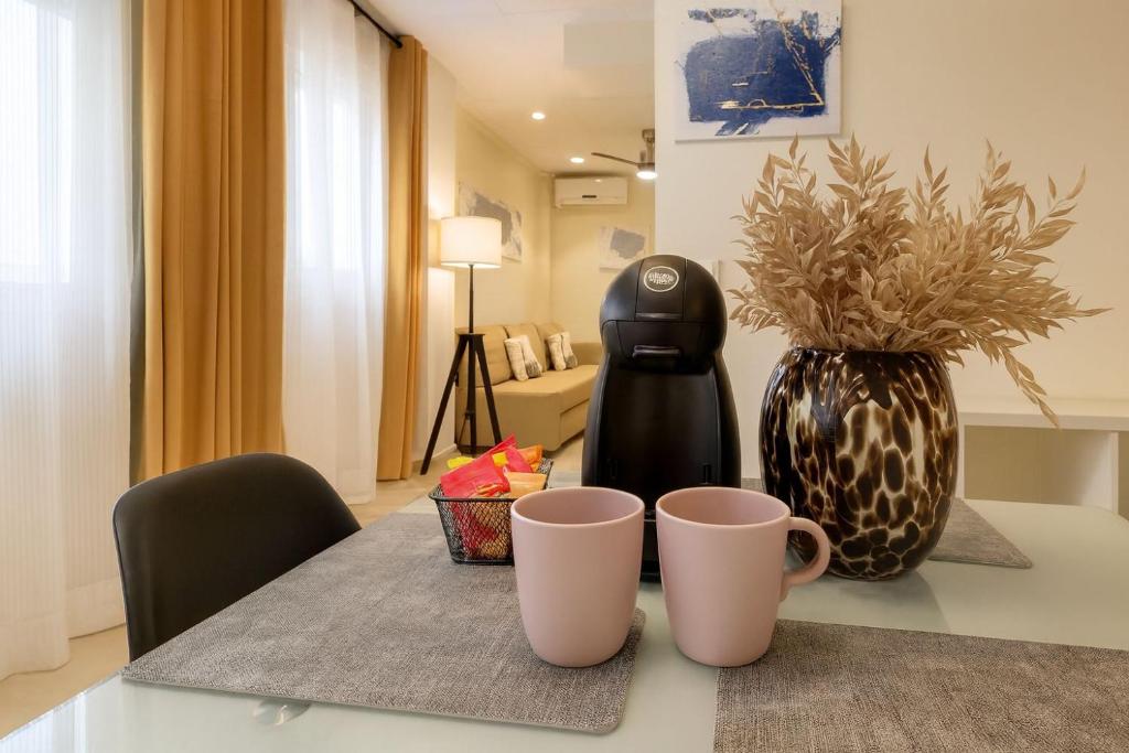 ein Tisch mit zwei Tassen und einer Vase darauf in der Unterkunft Triana Home centro ciudad in Murcia