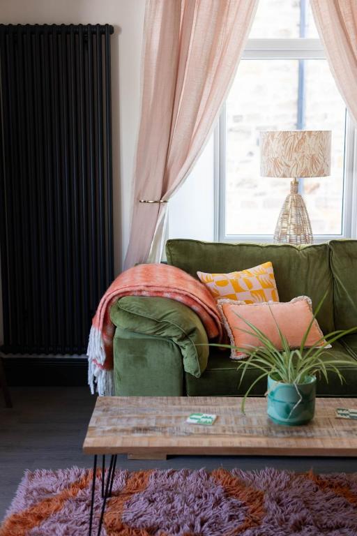 a green couch with pillows on it in a living room at THE LOFT Alnmouth in Alnmouth