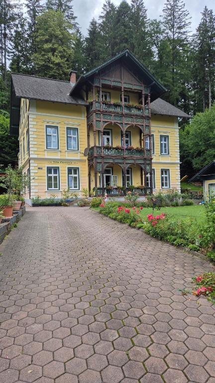 a large yellow house with a brick road in front of it at Villa Ohrenstein - Komfort Suite in Bad Ischl