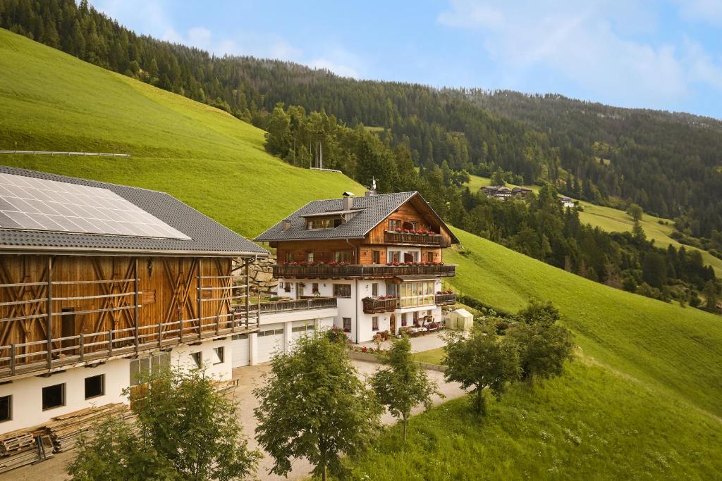 a large building in the middle of a green hill at Ferienwohnungen Kuentnerhof in San Candido