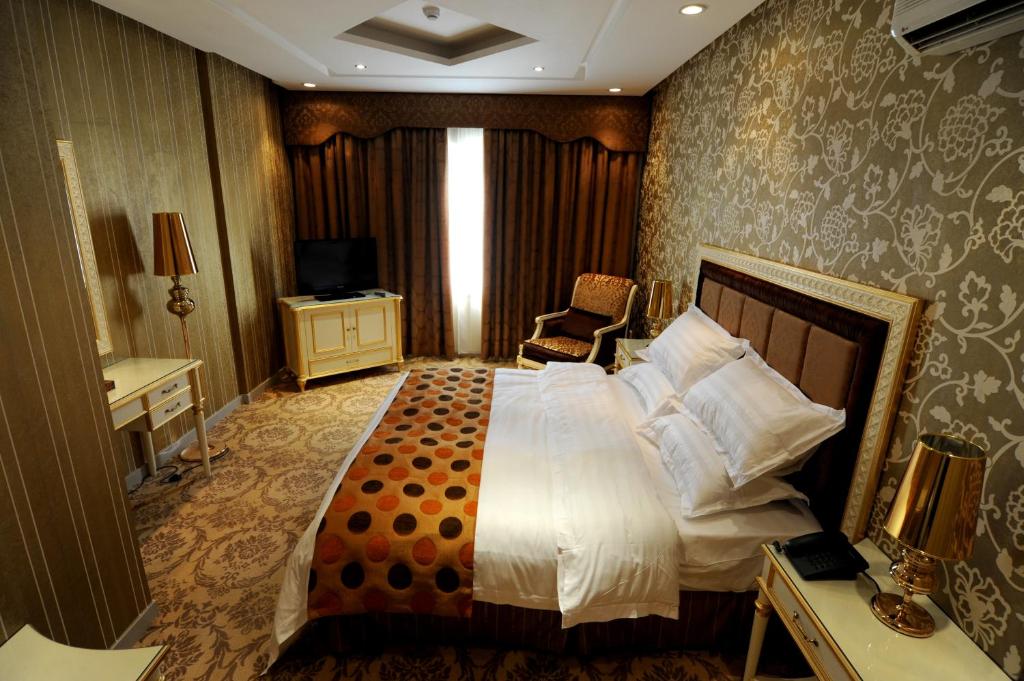 ein Hotelzimmer mit einem großen Bett und einem Stuhl in der Unterkunft Rose Garden Hotel in Riad
