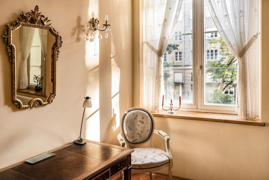 a chair in a room with a mirror and a desk at Cosmo - Old Money Apartment in Gdańsk