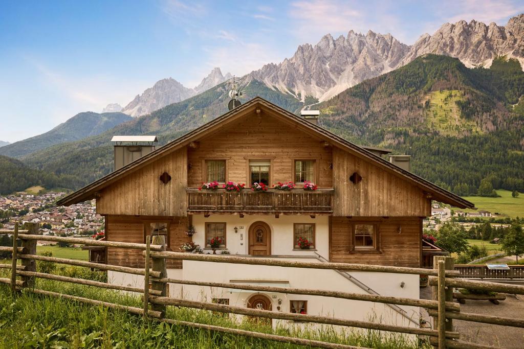 a house with flowers on a balcony in the mountains at Ferienwohnungen Kuentnerhof in San Candido