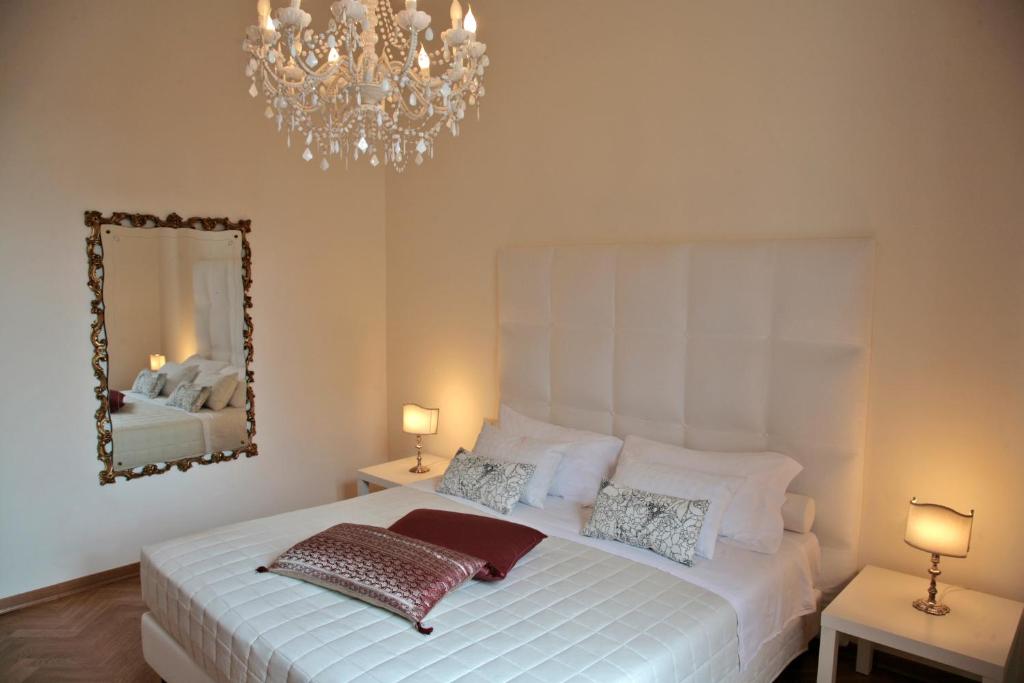 a bedroom with a white bed with a mirror and a chandelier at Exclusive Aparthotel La Reunion in Ravenna