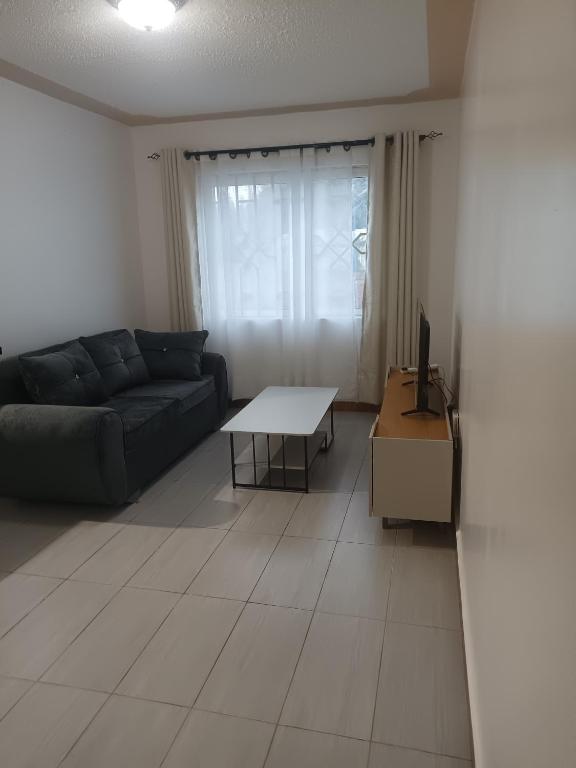 a living room with a couch and a table at 1 bedroom BNB Meru in Meru