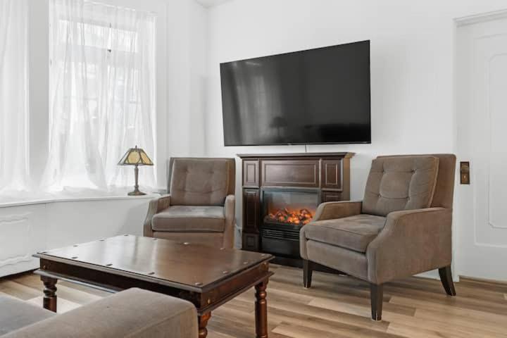 Una sala de estar con dos sillas y una chimenea. en Suite Jardin, en Quebec