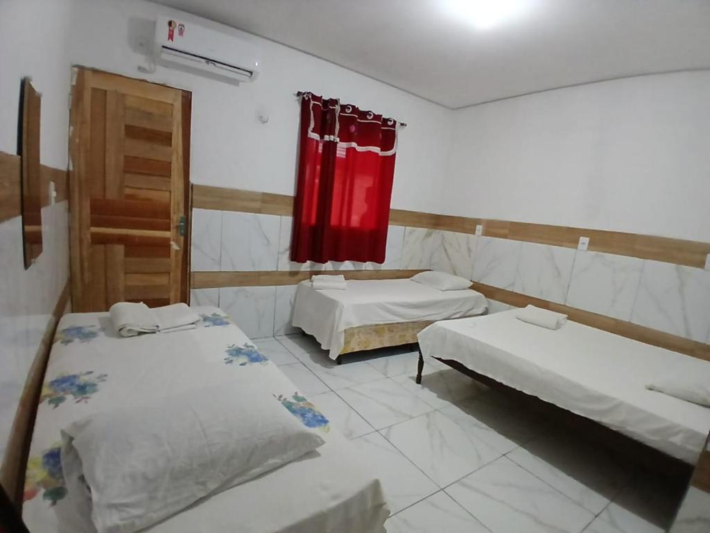 a room with two beds and a red curtain at Hotel Contorno in Santa Inês