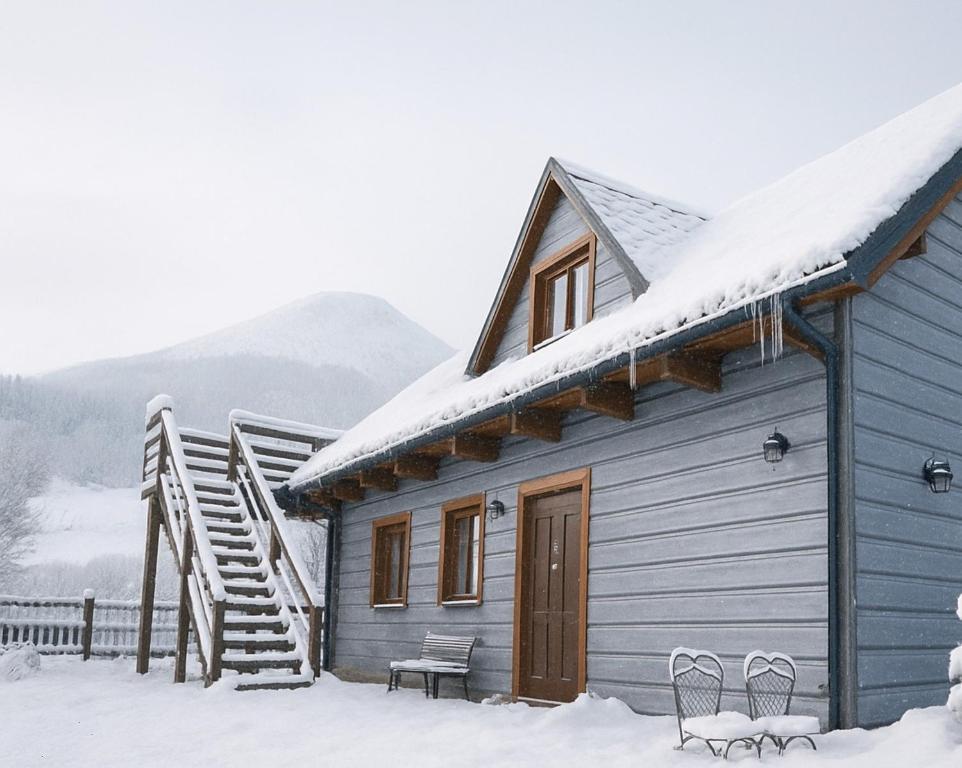 a blue house with snow on the roof at Telgártska chalupa pod Kráľovou hoľou - sauna & altánok in Telgárt