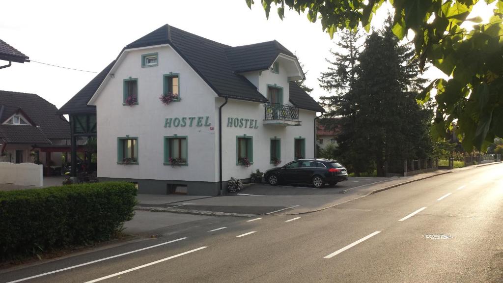 une voiture noire garée devant un bâtiment blanc dans l'établissement Mama's House, à Cerklje na Gorenjskem