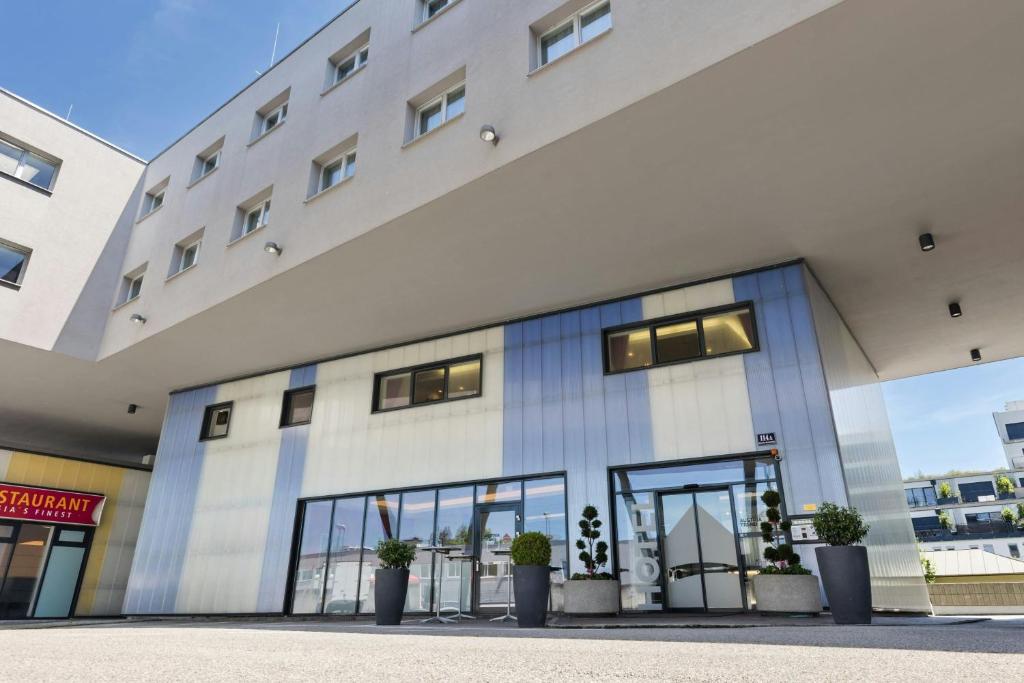 a large white building with windows and potted plants at Four Points Flex by Sheraton Salzburg Messe in Salzburg