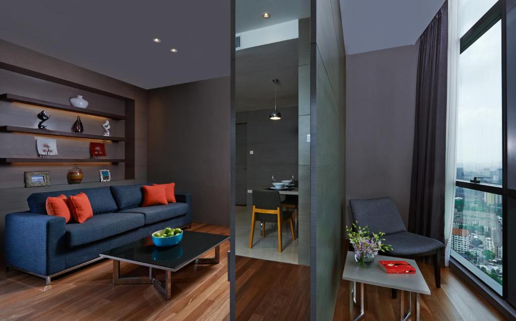 A bright living area with a blue sofa, high-rise outlook and a compact work nook.