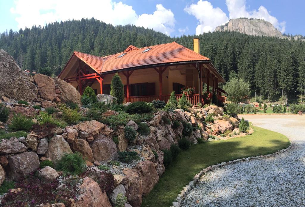 eine Hütte in den Bergen mit einer Felswand in der Unterkunft Lacu Roșu Mountain Lodge in Lacul Roşu