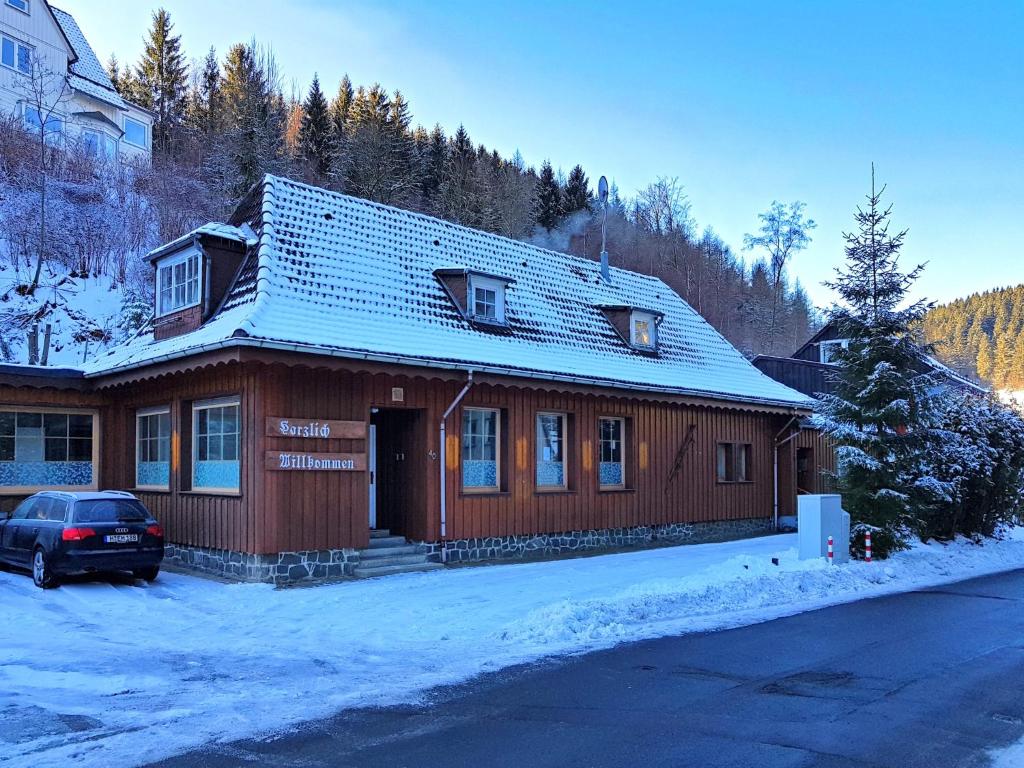 una casa de madera con un coche aparcado en la nieve en Wohnung in Wildemann nahe Harzwald, en Wildemann