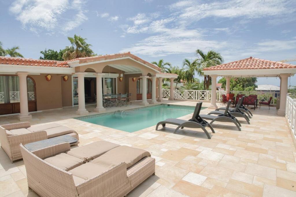 ein Swimmingpool mit Stühlen und ein Haus in der Unterkunft Villa Marrakesh, Cupecoy Beach - A Luxury Villa with Pool in Lowlands