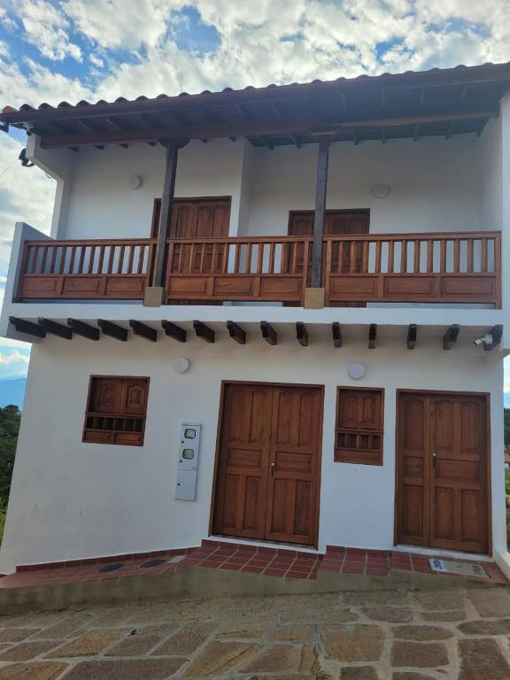 a white house with wooden doors and a balcony at Hospedaje Casa San Diego in Estación El Salto