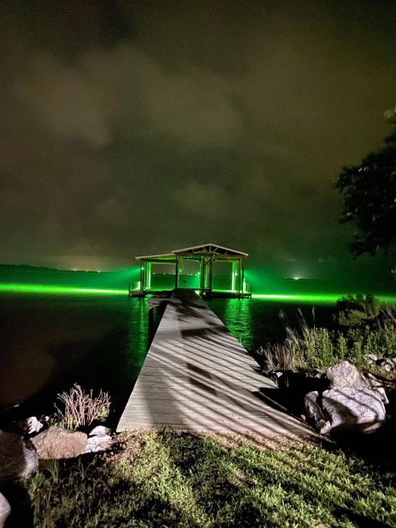 a dock with green lights on the water at night at Pelican Point Paradise in Hackberry