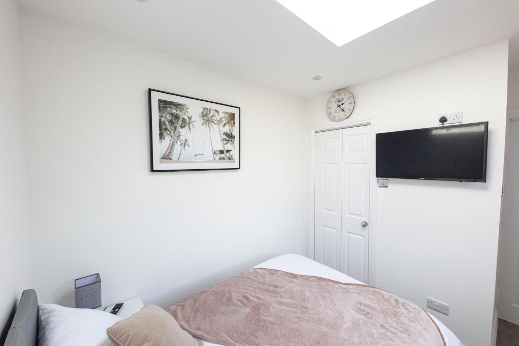a bedroom with a bed and a tv on the wall at Jayjay Guest House in Basildon