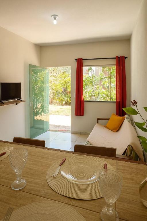 a room with a table and a bed with red curtains at Casa Toniatti 2 in Barra Grande