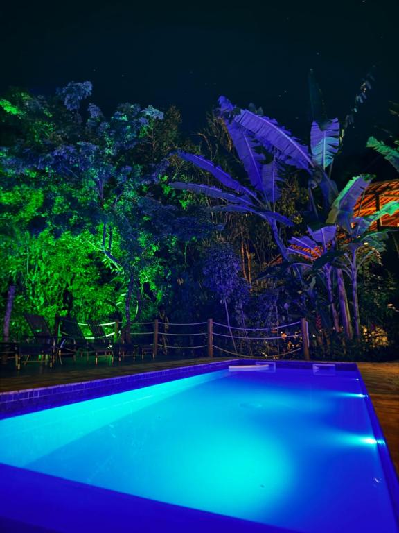 a swimming pool lit up at night at Jardim Botânico Casa Rossa Bungalows & Apartments in Morro de São Paulo