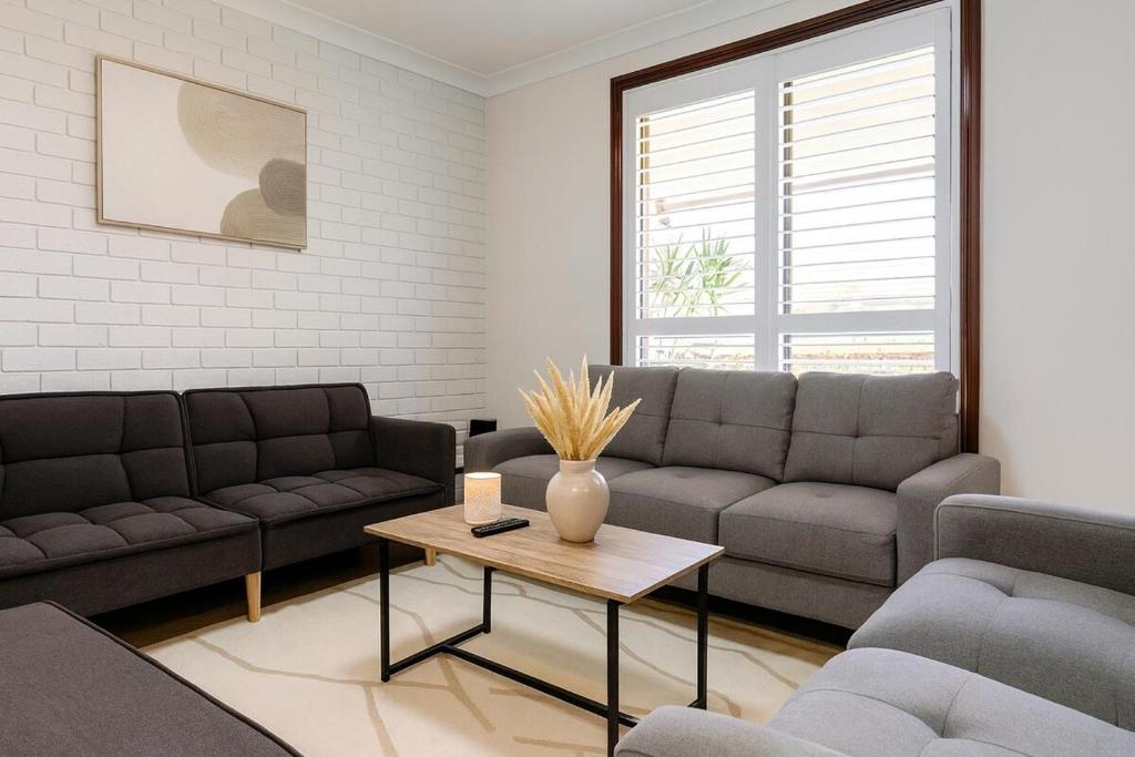 a living room with two couches and a coffee table at 3 Bedroom Deluxe Family Home in Rooty Hill