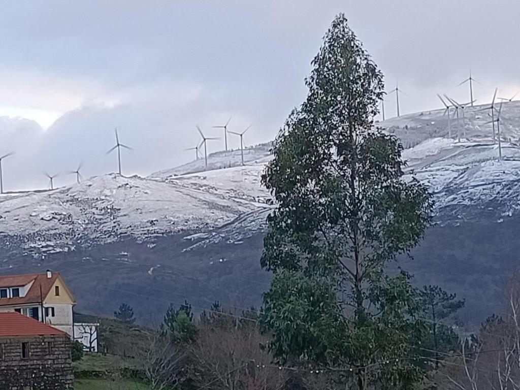 una collina coperta di neve con turbine eoliche su una montagna di Pomares Country House a Paderne
