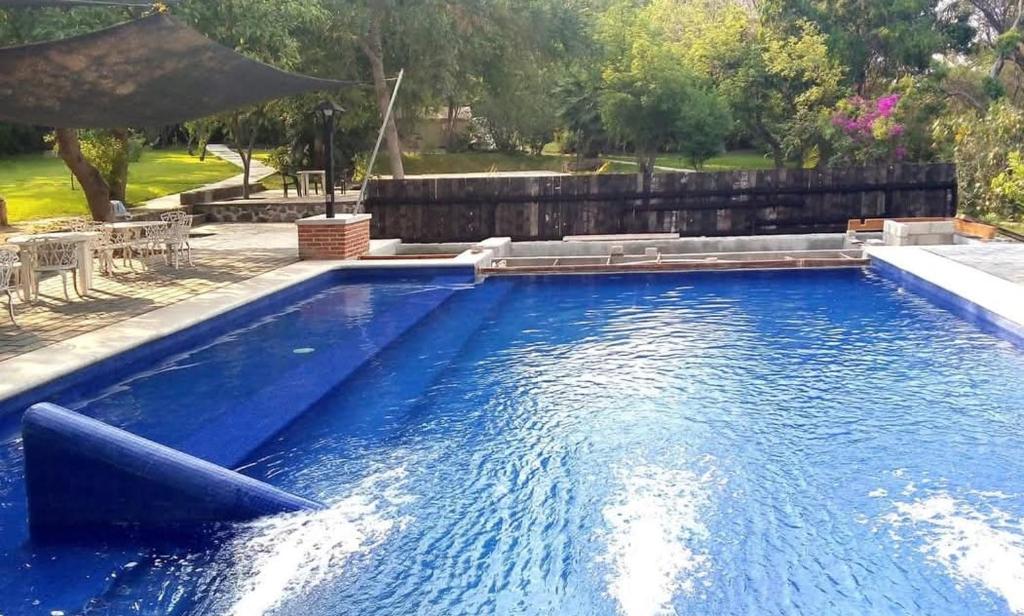 a pool with blue water in a backyard at Hostal TAPALEHUI in Xoxocotla