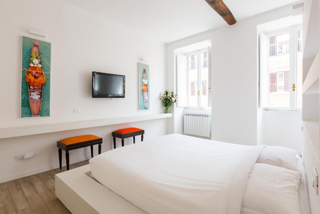 a white bedroom with a white bed and two stools at Deluxe Ripetta 41 in Rome