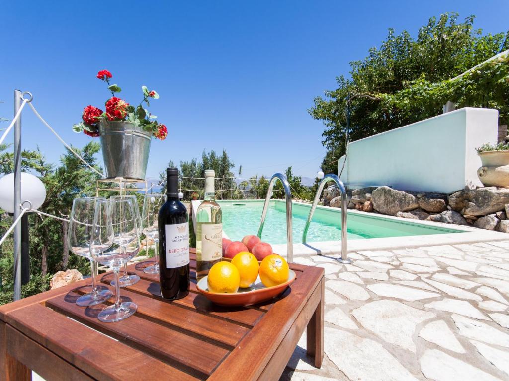 una mesa con copas de vino y fruta junto a una piscina en Villa Antico Pozzo piscina privata SPA, en Castellammare del Golfo