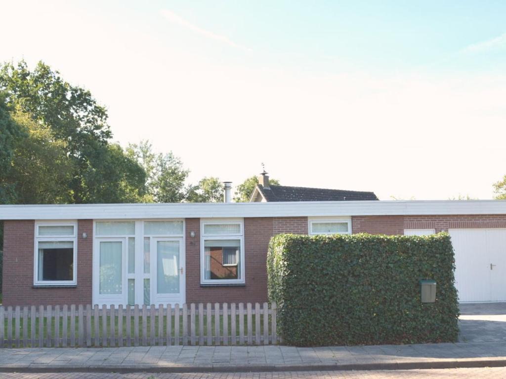 a brick house with a hedge in front of it at with large, fenced garden DL108 in Domburg