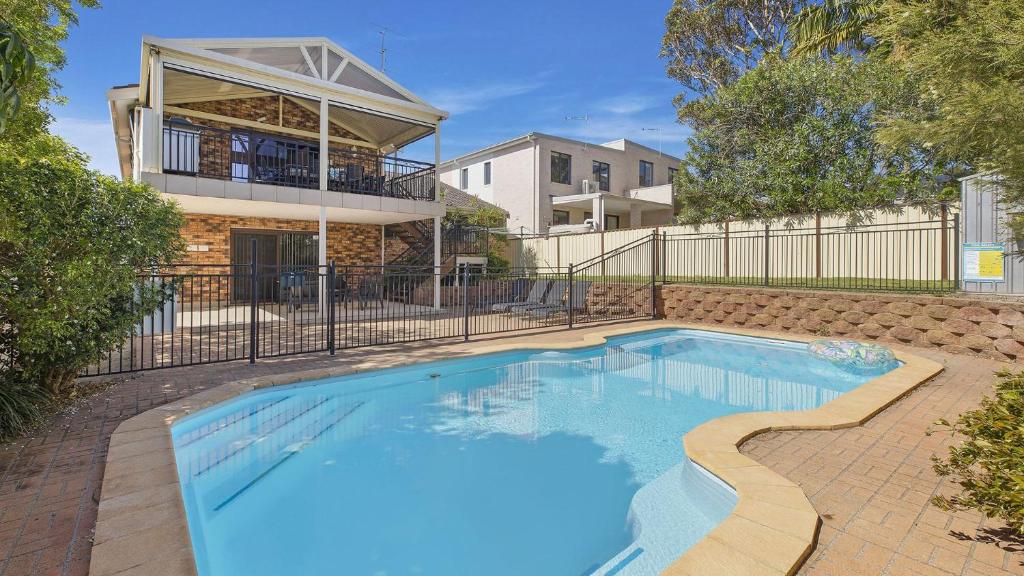 a swimming pool in front of a house at Sunset On View - Picturesque Coastal Setting With Pool in The Entrance