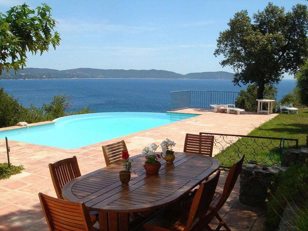 Una mesa de madera con sillas junto a una piscina. en 1-bedroom villa in Cote d'Azur, en Cavalaire-sur-Mer